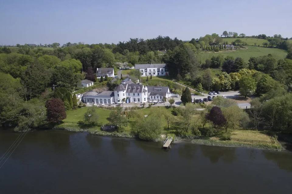 Innishannon House Hotel from an aerial view. The hotel is surrounded by forest and lush lawns.