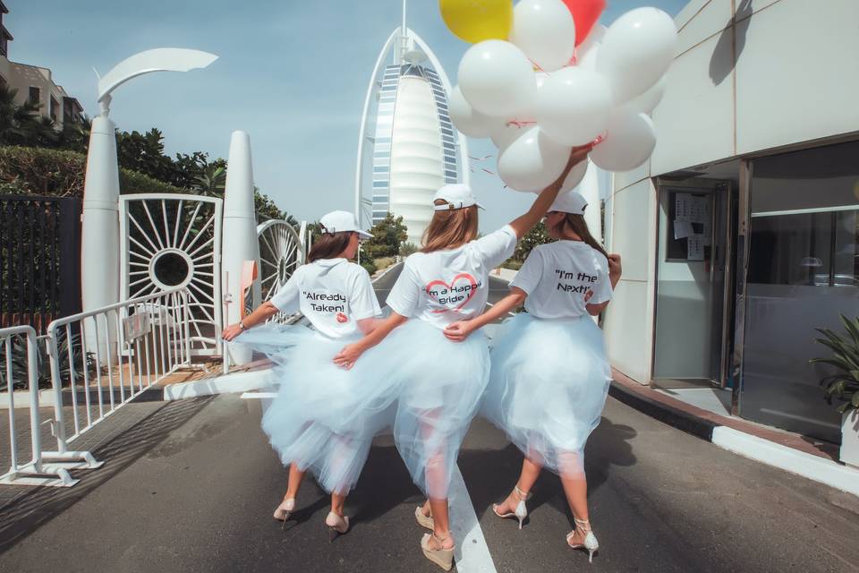 Three women walking wearing white skirts and novelty hen party tshirts.