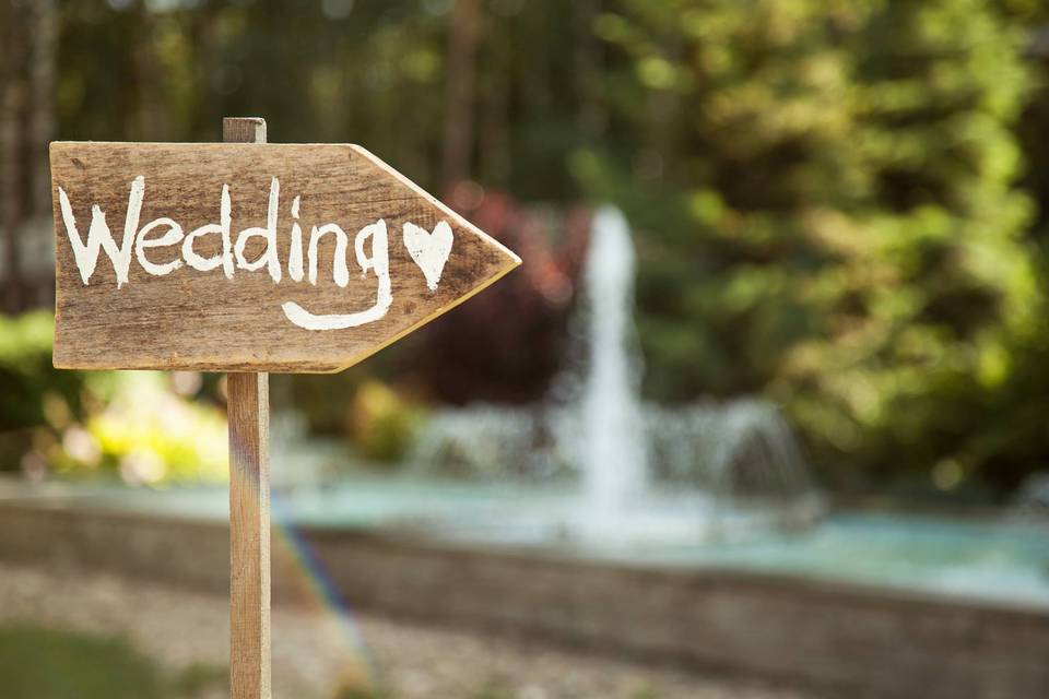 A handmade wooden wedding sign points guests in the right direction.