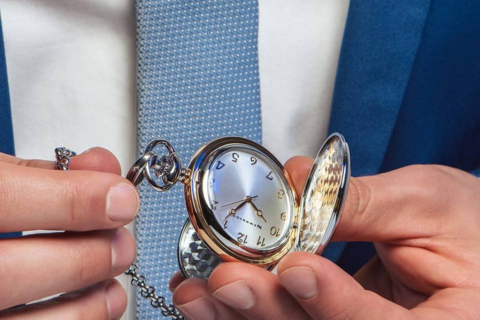 Image of hands holding a pocket watch with a white face, gold hands and numbers, and silver and gold exterior, on a silver chain.