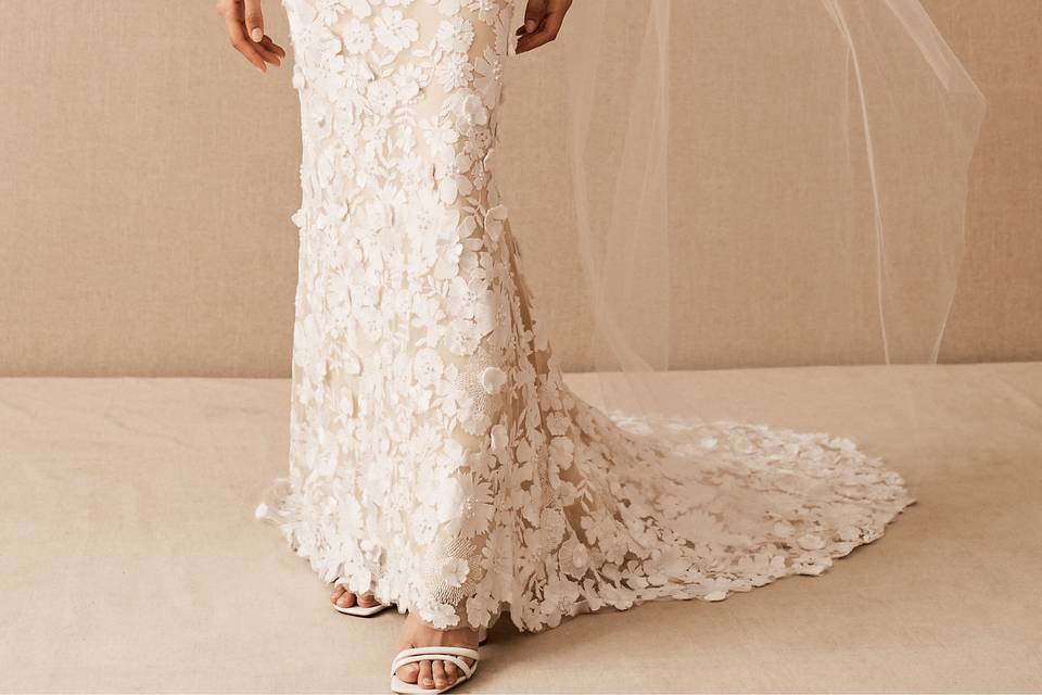 A woman poses in a modern, embroidered tulle wedding dress that features an eye-catching floral pattern