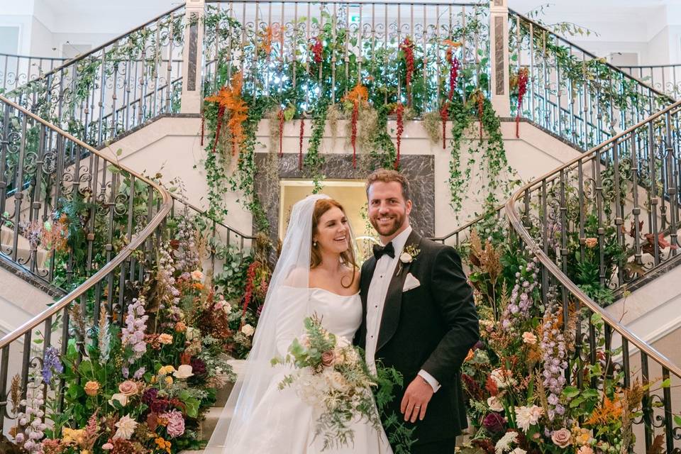 A happy couple standing on a grand staircase